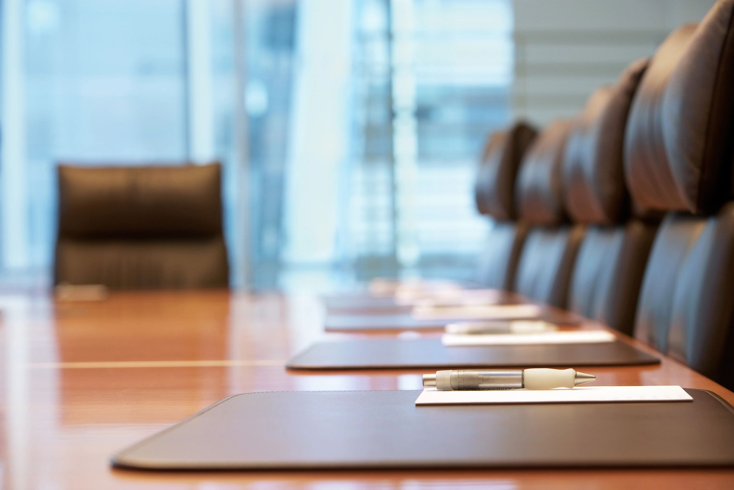 A corporate boardroom with a polished wooden conference table and leather chairs